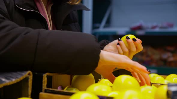 Hands of the Girl Choose Fresh Lemon on the Shelves of the Hypermarket
