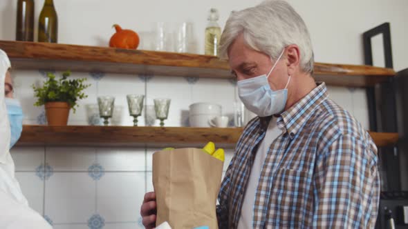 Volunteer in Safety Mask and Overall Delivering Groceries for Elderly Man