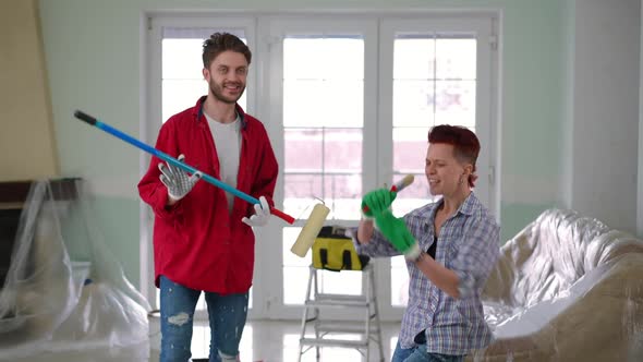 Joyful Carefree Couple Having Fun Painting New House Living Room Indoors