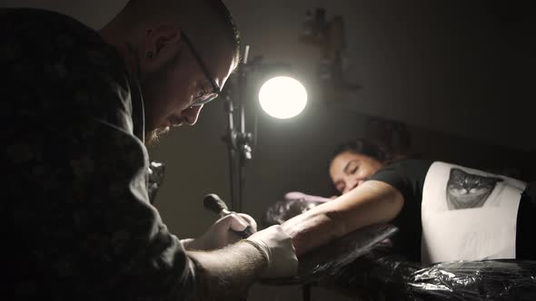 Young master making tattoo on skin of client