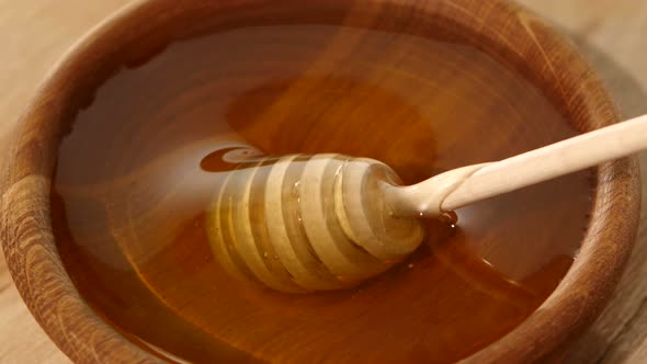 Using Spoon for Honey in Wooden Bowl
