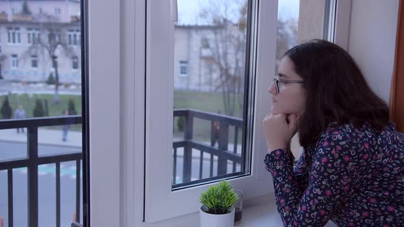 A Brunette Girl in Glasses Stands at the Window Waiting for a Meeting Side View Copy Space