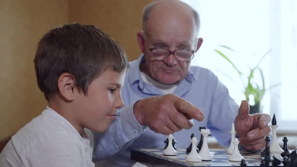 Game of Chess, a Cute Intelligent Male Child, Together with an Elderly Man in Glasses for Sight