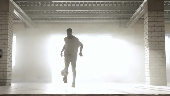 Young Black Guy Trains with a Soccer Ball at Indoors