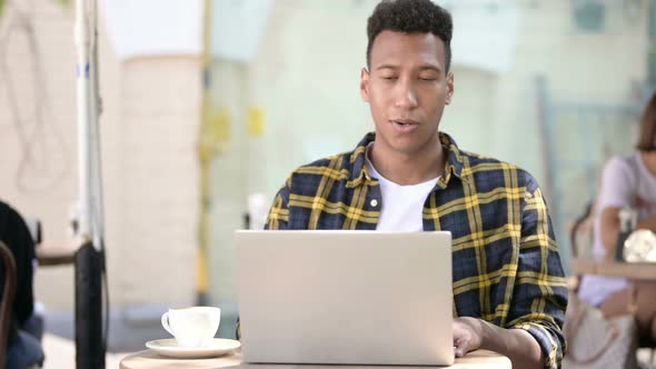 Online Video Chat on Laptop By Young African Man, Outdoor Cafe