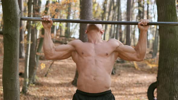 Strong Naked Guy Pulls Up On Pole. Exercise Emphasizes All The Muscles Of The Man.