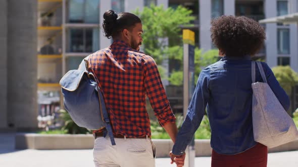 Diverse couple walking on the street holding hands smiling and talking