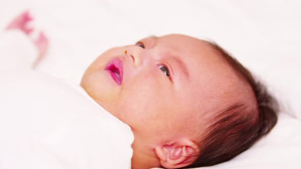 Crying Newborn baby boy lying on white bed at home