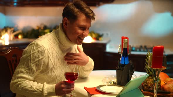 Side View Happy Man Waving at Tablet Video Chat Talking Sitting at Table with Red Wine