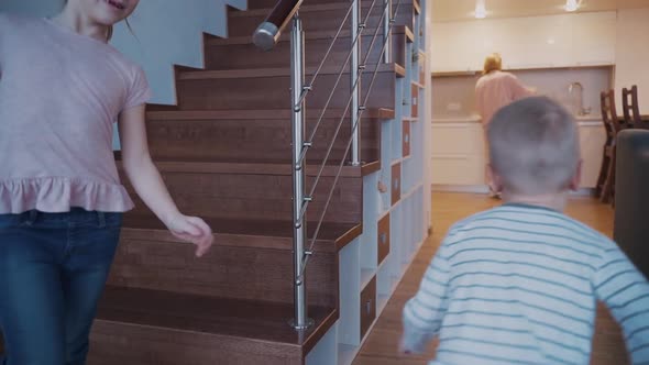 Two Small Kids Run To Mother in the Kitchen