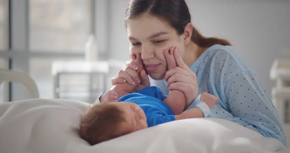 Mother Playing with Newborn Baby After Labor in Hospital