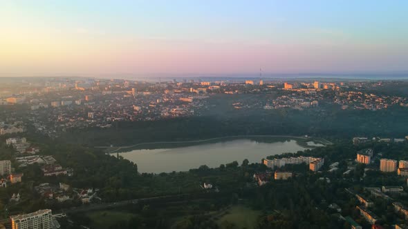 Aerial drone view of Chisinau at sunrise. Park with lush greenery and lake. Panorama view of multipl