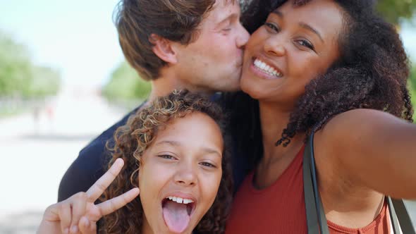 Pretty multiethnic family recording video at the camera and posing in the park