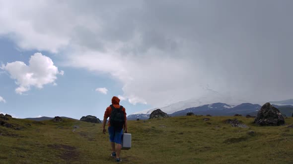 A guy with a Hiking backpack climbs the mountain on the background