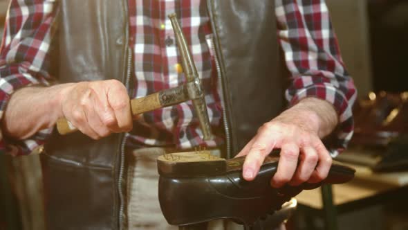 Shoemaker hammering on a shoe in workshop