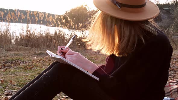 Millennial Woman Caucasian Blonde Woman with Beige Hat in Black Sweater Write on Notebook in the