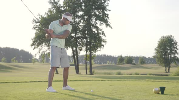 Portrait Handsome Successful Middle Eastern Golfer Swinging and Hitting Golf Ball on Beautiful