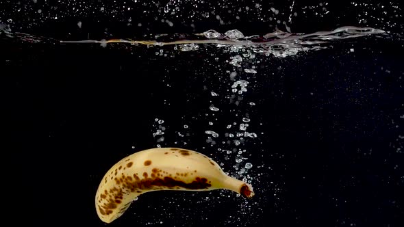 A ripe banana being dropped into water in slow motion.