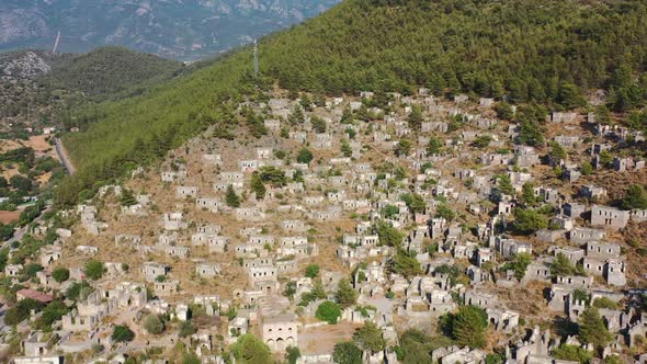 aerial drone flying backwards over abandoned homes and ruins of a greek village on a mountain called