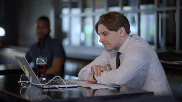 Overworking Caucasian Man Falling Asleep on Bar Counter with Blurred Interracial Couple Meeting at