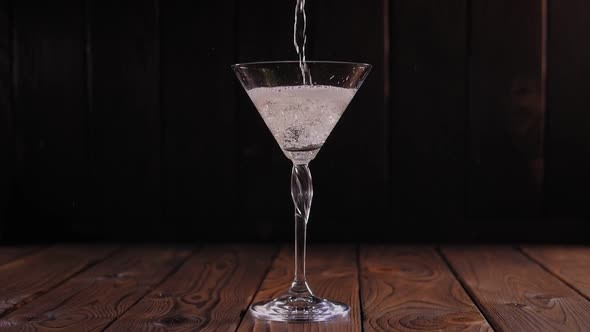 Close-up of a Martini Being Poured Into a Glass on a Wooden Surface