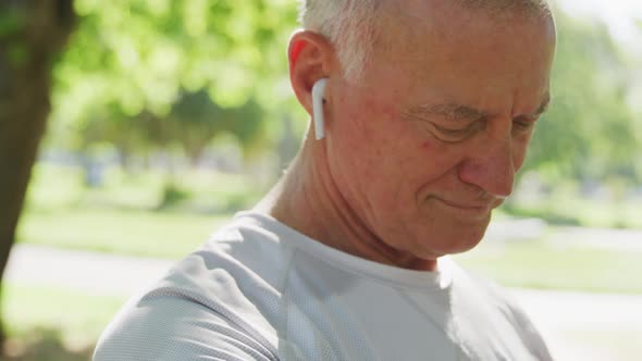 Senior man using wireless earphones in the park