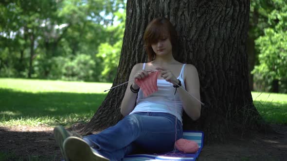 Young Girl Doing Knitting in the Park Under a Tree