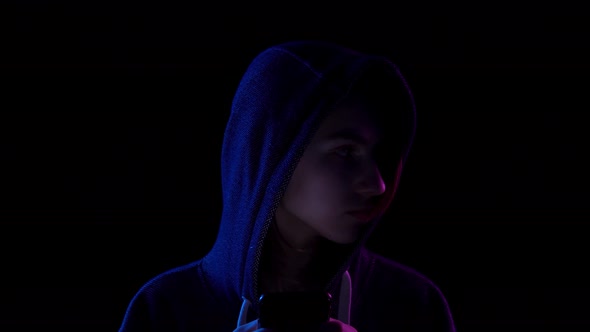 Closeup of a Young Woman in a Hood with a Phone in Her Hands. A Hacker Makes a Hack Through the