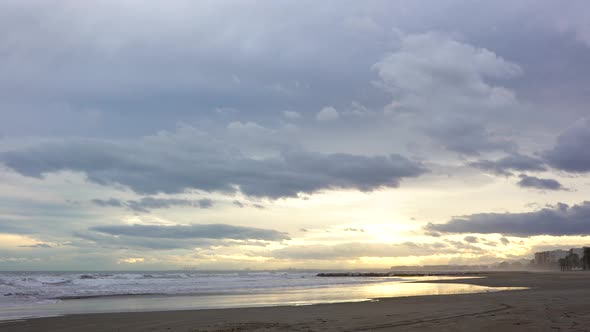 Time lapse, storm clouds loom over Mediterranean beach at sunset