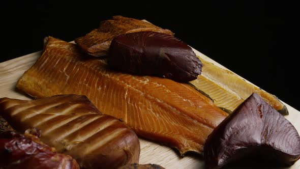 Rotating shot of a variety of delicious, premium smoked meats on a wooden cutting board