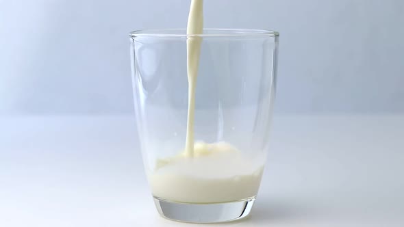 Pour the splash of milk into a clear glass on a white table.
