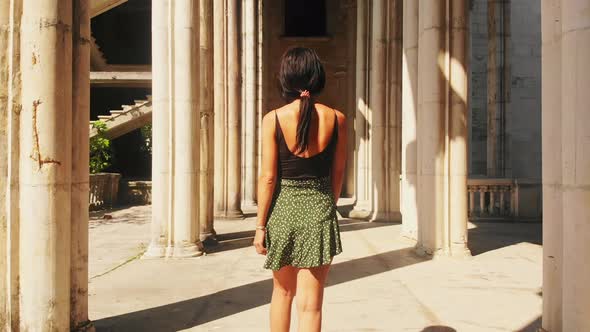 Slow Motion Girl Walks Around Columns In Historical Site