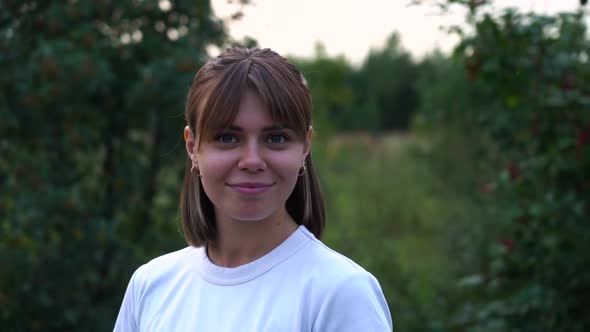 Portrait Young Attractive Smile Woman Look at Camera in Park or Woods in White T-shirt Slow Motion.