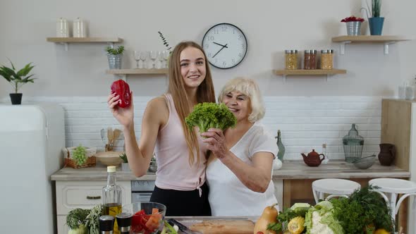 Senior Grandmother with Granddaughter Recommending Eating Raw Vegetable Food. Vegetable Diet