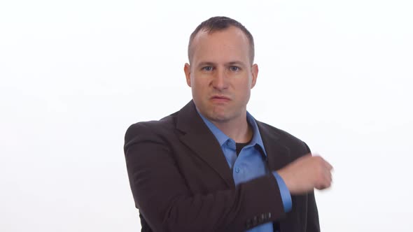 Angry man threatens camera with slit throat gesture and pointing on a white background.