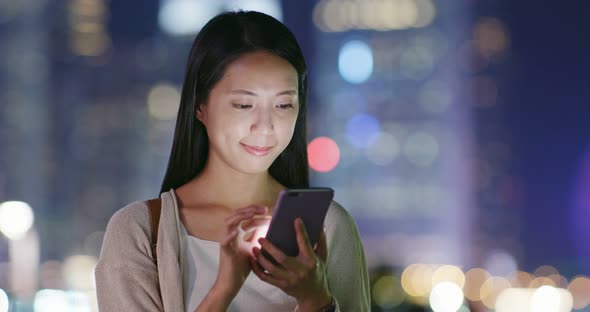 Woman look at smart phone in city at night