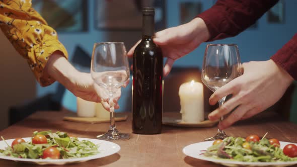 Young Couple in Love Serving Dinner Talking and Drinking Red Wine Cozy Saint Valentines Day