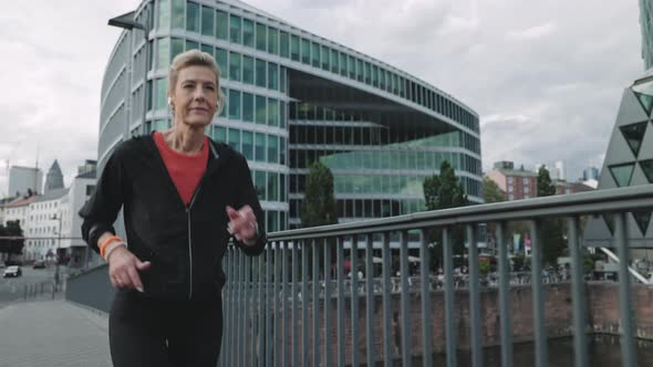 Aged Woman in Active Clothes Jogging on City Street