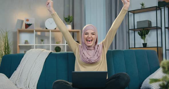 Arabic Woman in Hijab Rejoycing from Good News She See on Laptop Screen with Raise Hands