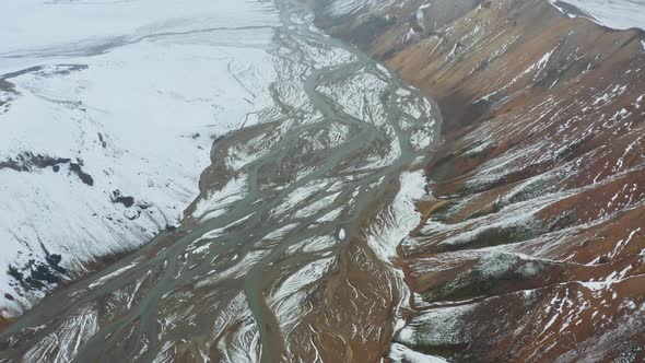 Drone Over Mountain Peaks And Snow Covered Landscape With River