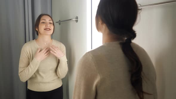 Brunette Girl Measures the Clothes in a Fitting Room