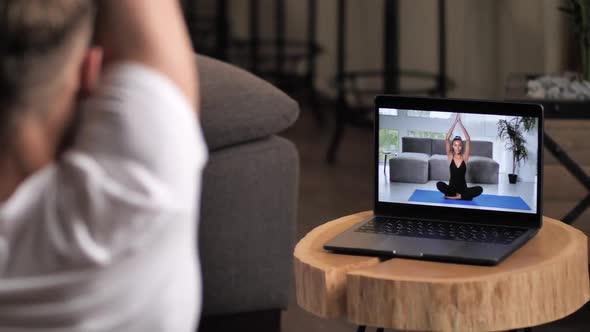 Man Practicing Yoga Online with Woman Instructor