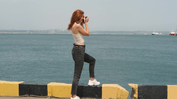 Beautiful Young Woman Photographer with Red Hair Walks in the Port of Odessa