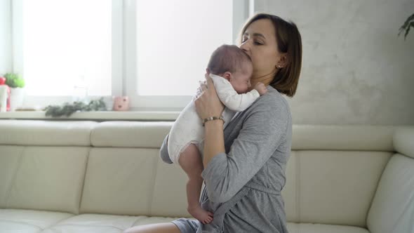 Happy Young Mother Holding Her Newborn Baby in Her Arms