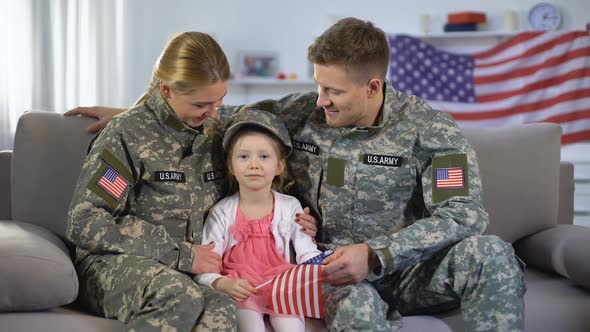 Happy American Soldiers Couple and Daughter With US Flag Smiling at Camera