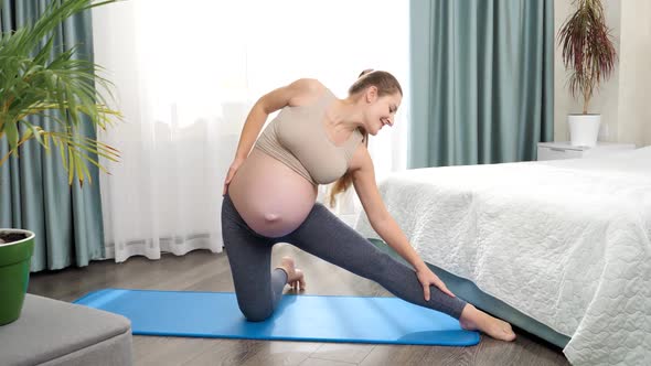 Slow Motion of Young Smiling Pregnant Woman Stretching and Warming Up Before Doing Fitness at Home