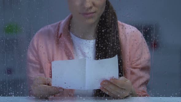 Upset Lonely Lady Sitting Behind Rainy Window and Reading Letter, Missing Family