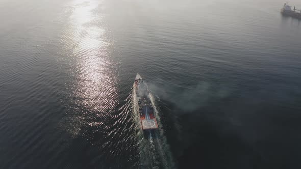 Drone View of a Modern Corvetteclass Ship Going Out to Sea Under the Bridge