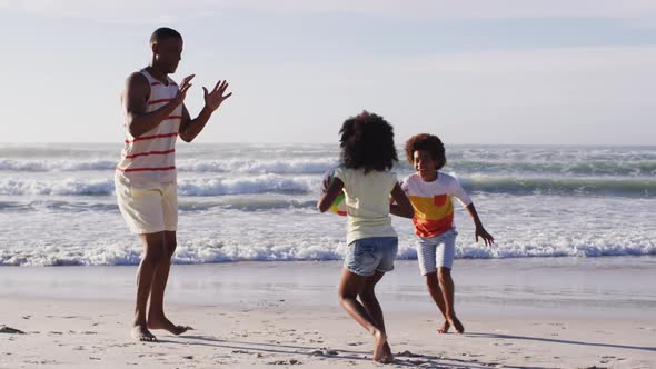 African american father and his children playing with a ball on the beach