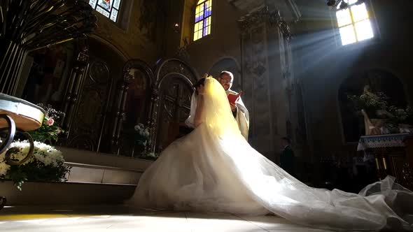 The Bride Swears to God Against the Backdrop of Sunlight in a Beautiful Christian Church